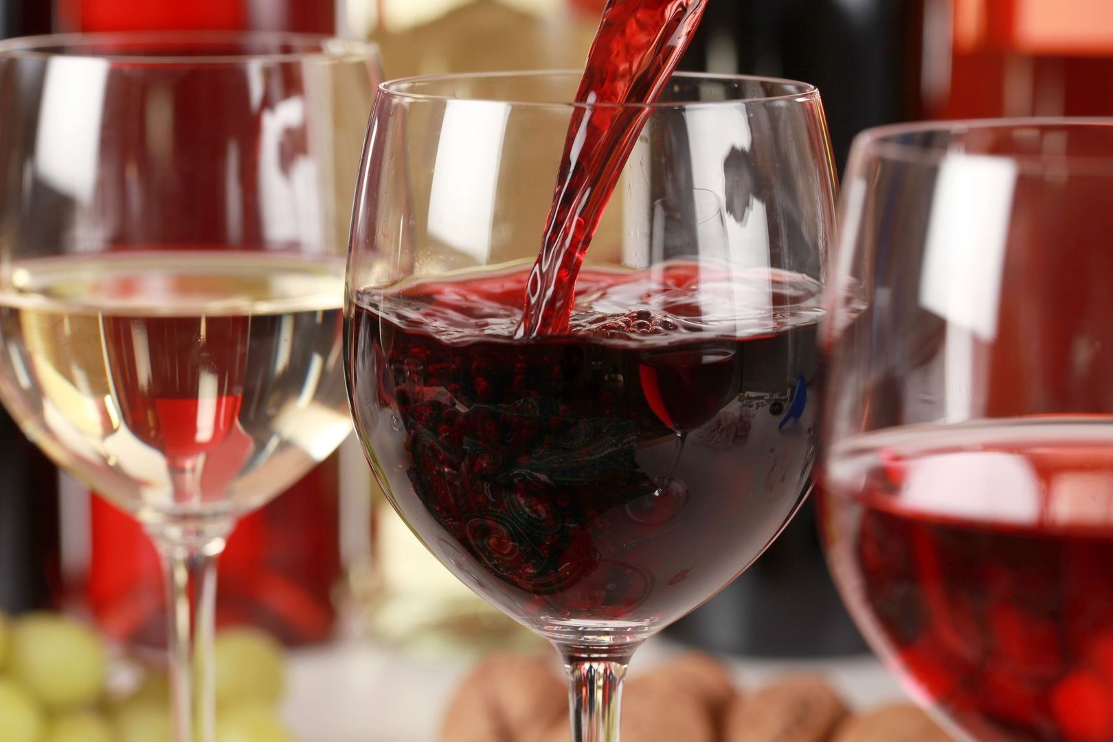 Ein Rotweinglas in das gerade Rotwein eingeschenkt wird